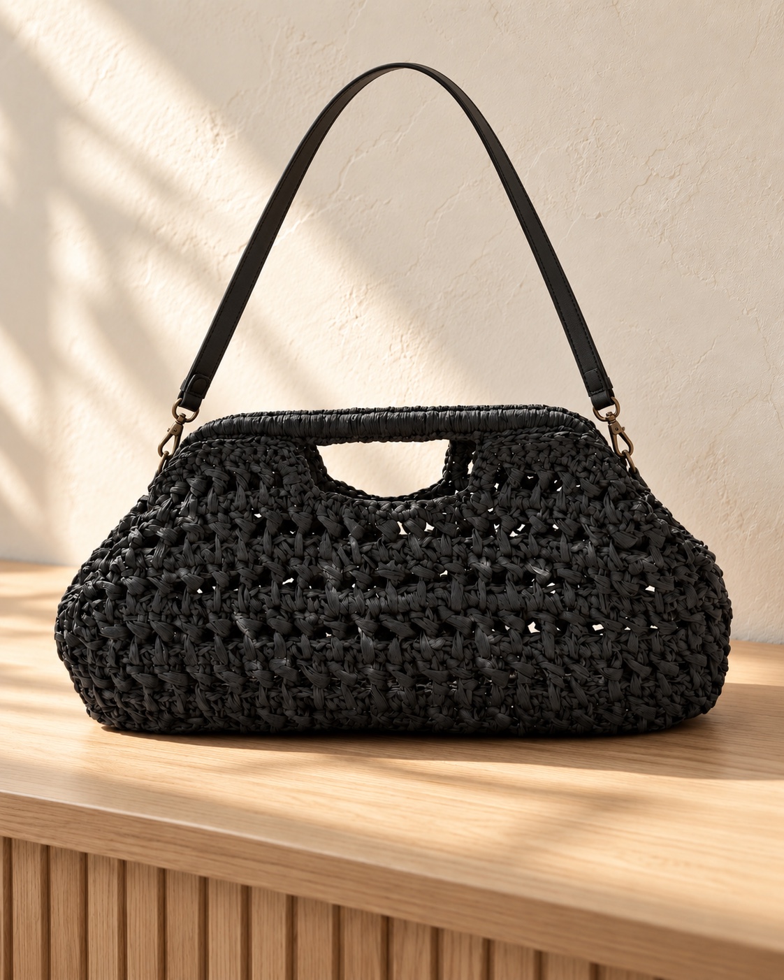 Schwarze Tasche mit offener Struktur, integriertem Griff und Schulterriemen.