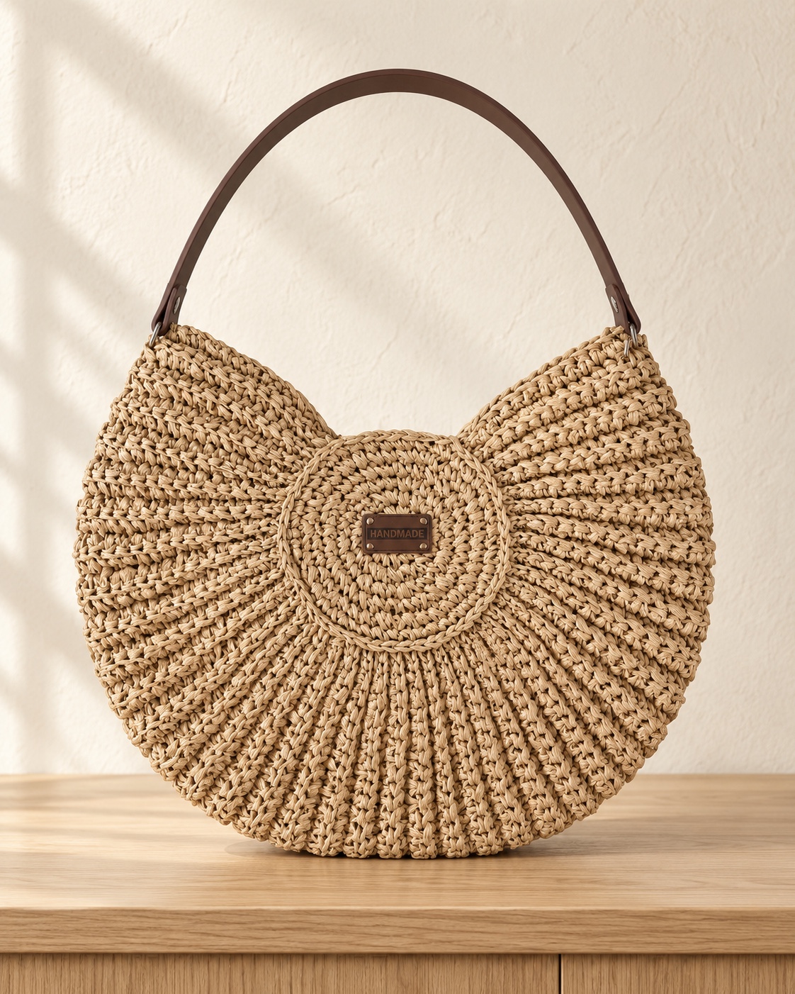 Naturbeige Tasche mit rundem Muster und braunem Henkel.